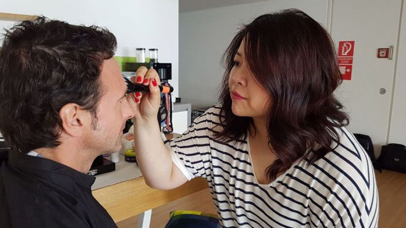 Maskenbildnerin Bigshan Choi schminkt einen Protagonisten.