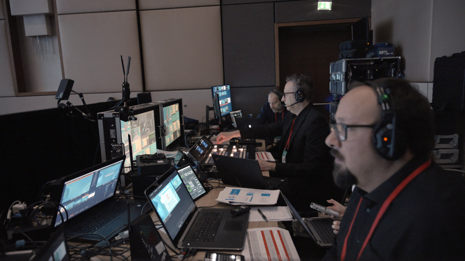 Drei Männer sitzen während eines Corporate Events in der Regie - mit Headsets vor Bildschirmen.