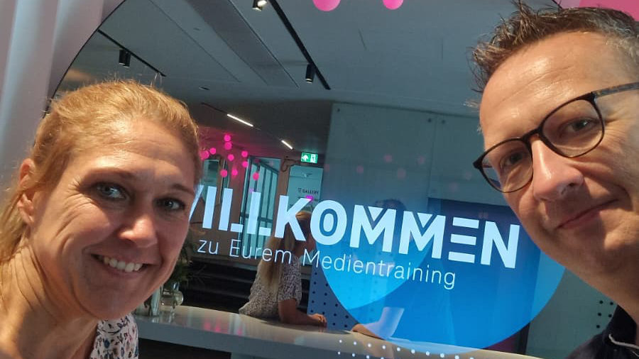 Anja Meyer und Philipp Klietz stehen vor dem Schriftzug: Willkommen zu Eurem Medientraining